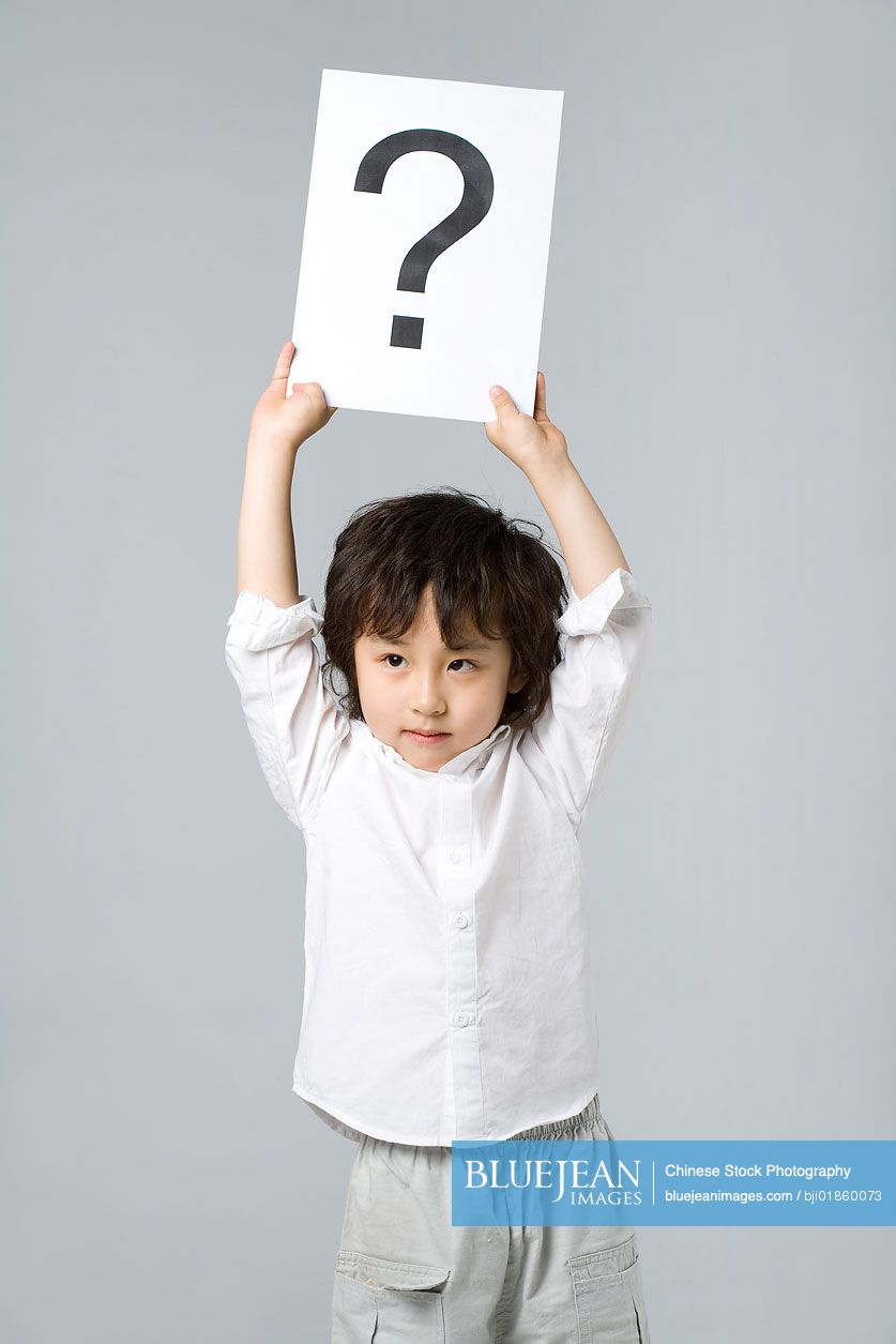 Little Chinese boy holding a sign with a question mark