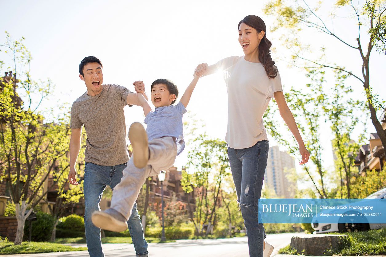 Happy young Chinese family playing outdoors