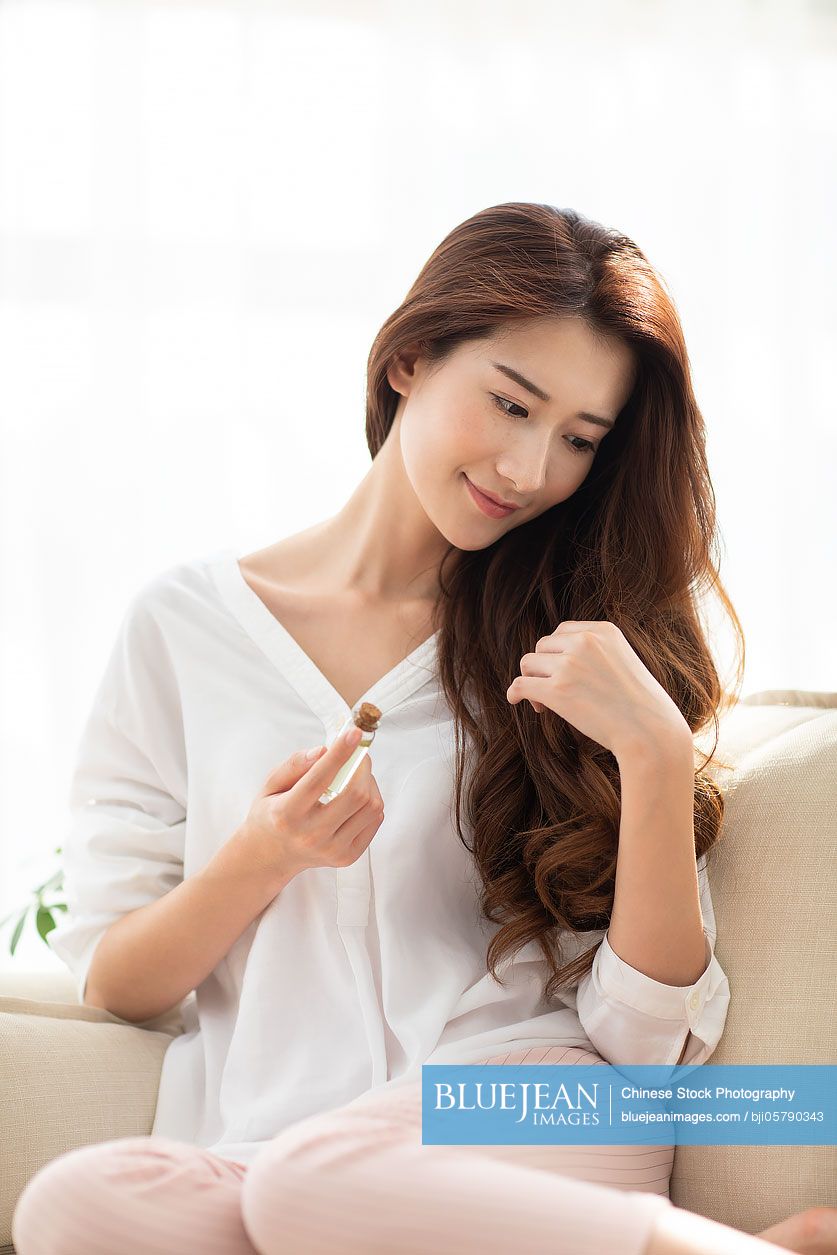 young-chinese-woman-applying-essential-oil-on-hair-high-res-stock-photo