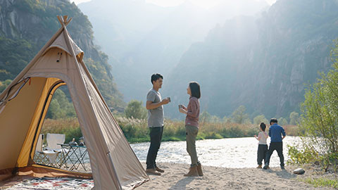 Happy young Chinese family camping outdoors