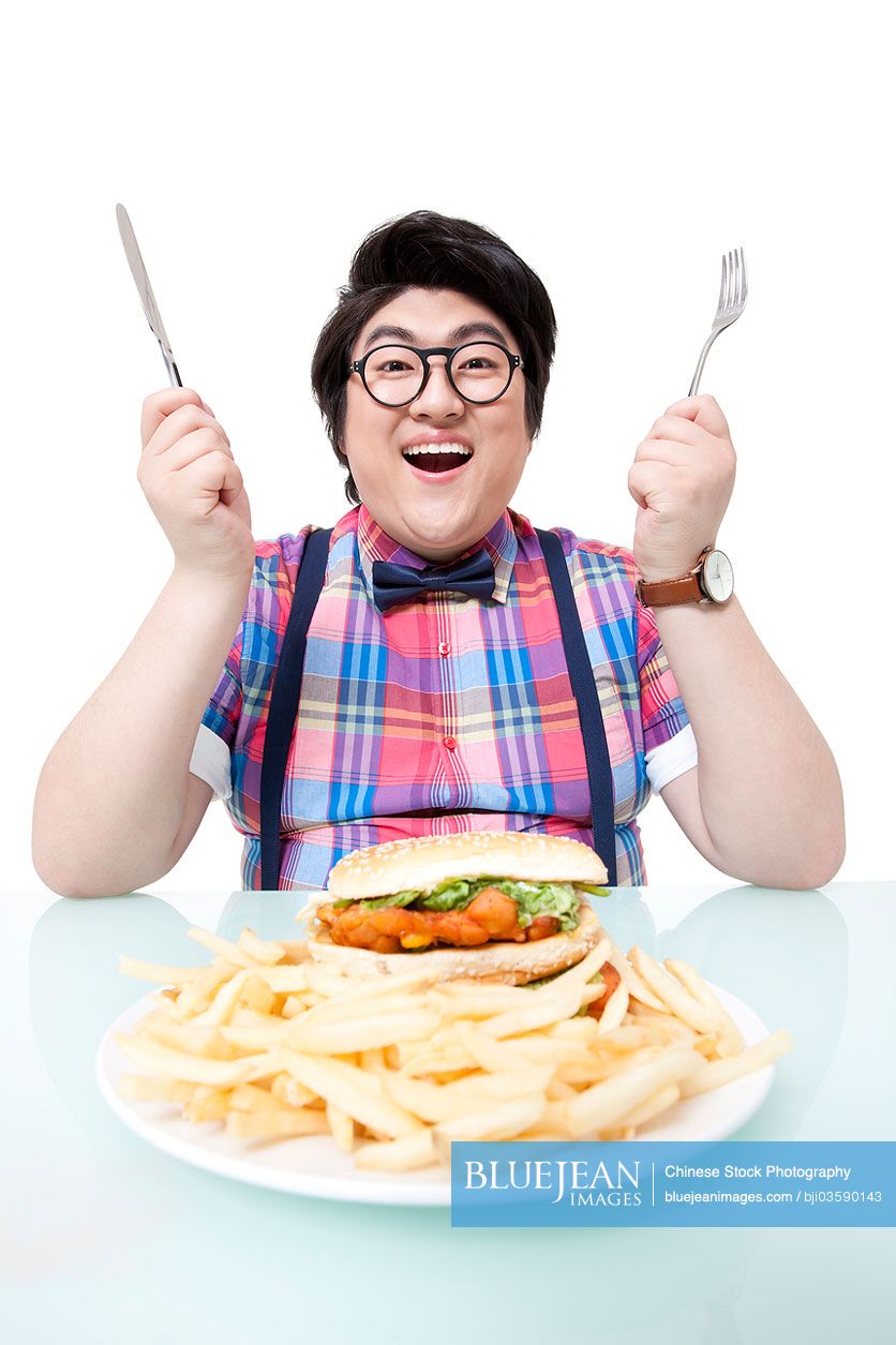 Overweight young Chinese man eating fast food