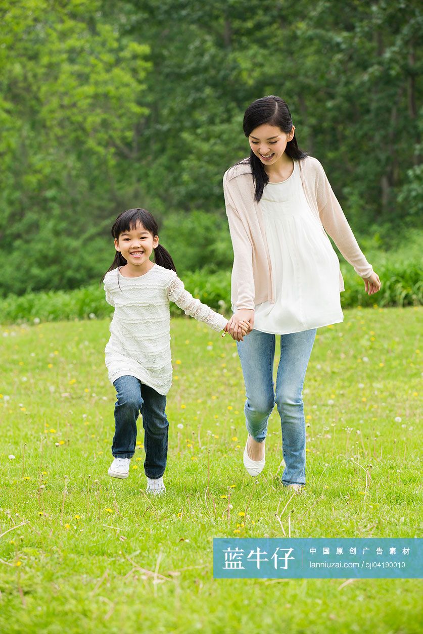 快乐的母女手牵手在草地上奔跑