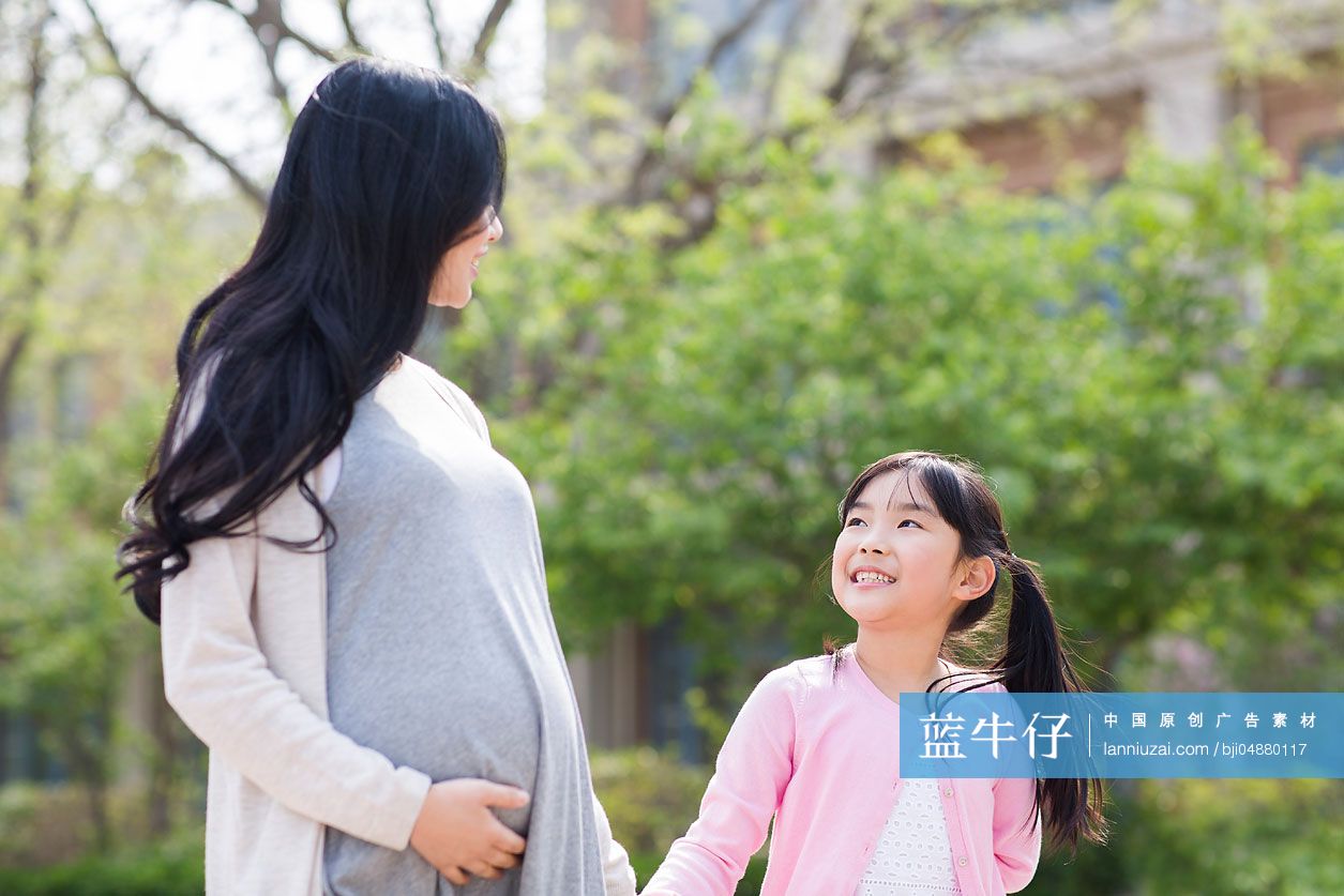怀有身孕的妈妈和女儿手牵手散步
