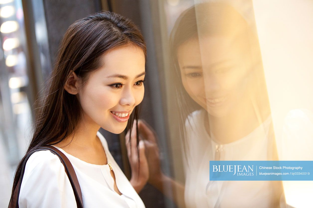 Beautiful young Chinese woman doing window shopping in Hong Kong