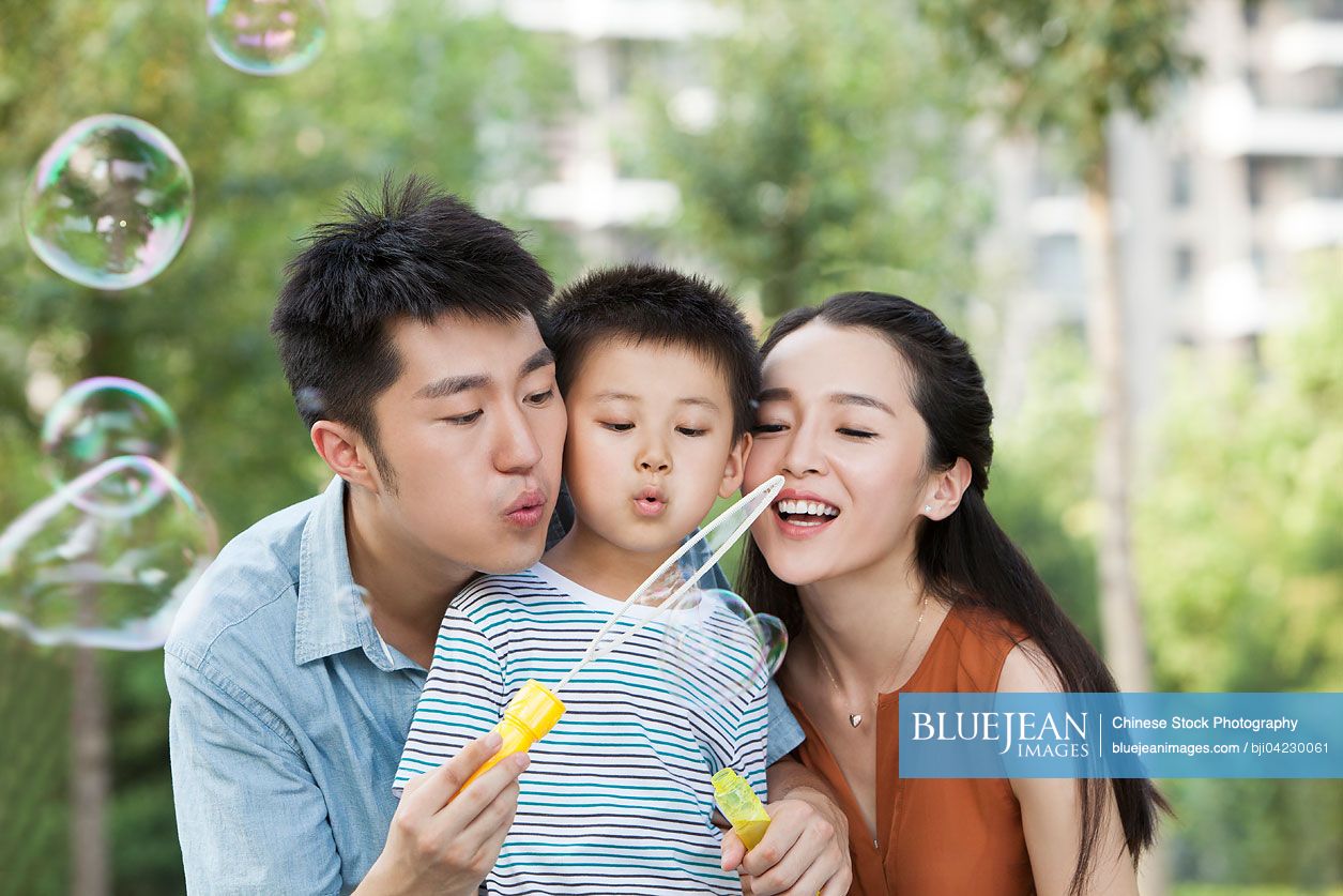 Happy young Chinese family blowing bubbles