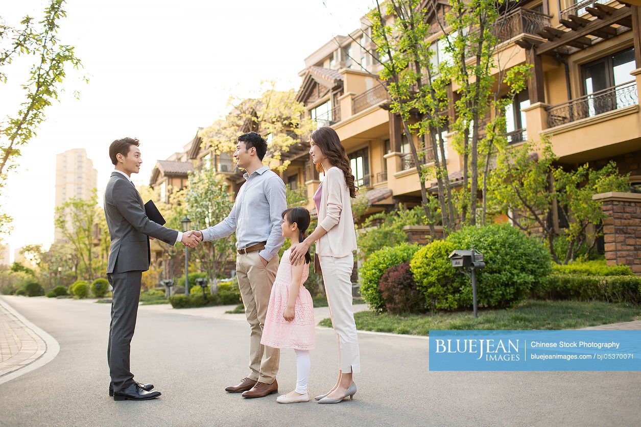 Happy young Chinese family shaking hands with realtor