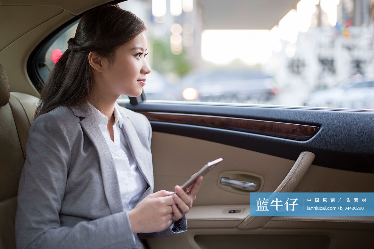 商务女士坐在汽车后座使用手机