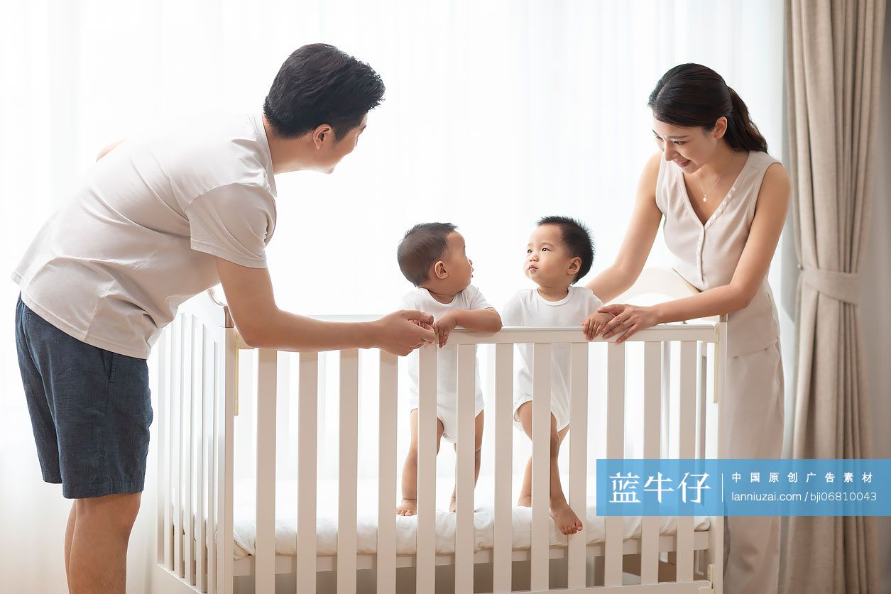 年轻父母在家陪龙凤胎宝宝玩耍