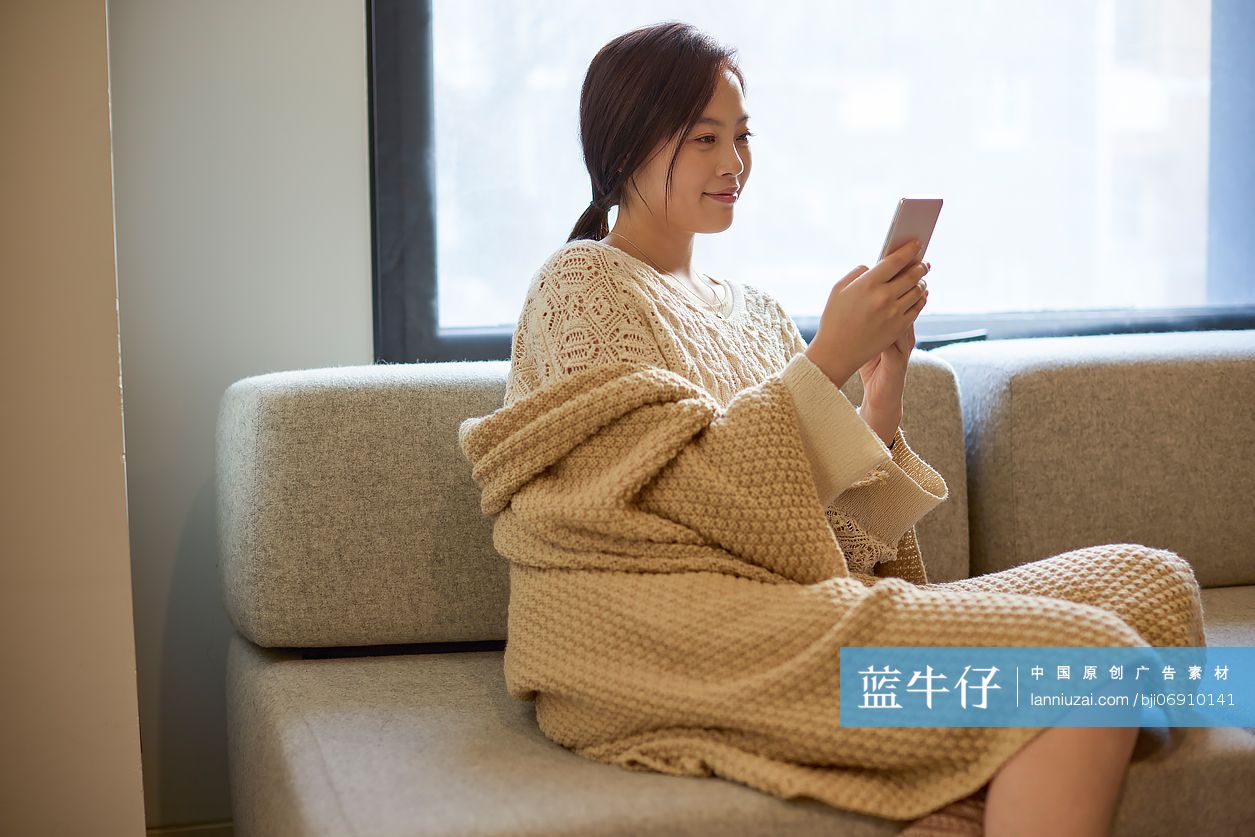 年轻女性坐沙发上玩手机