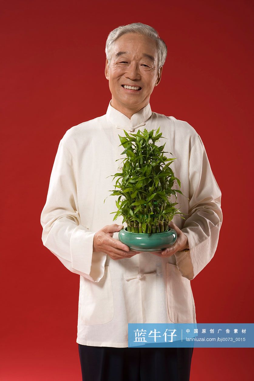 一位老人手拿一盆竹子
