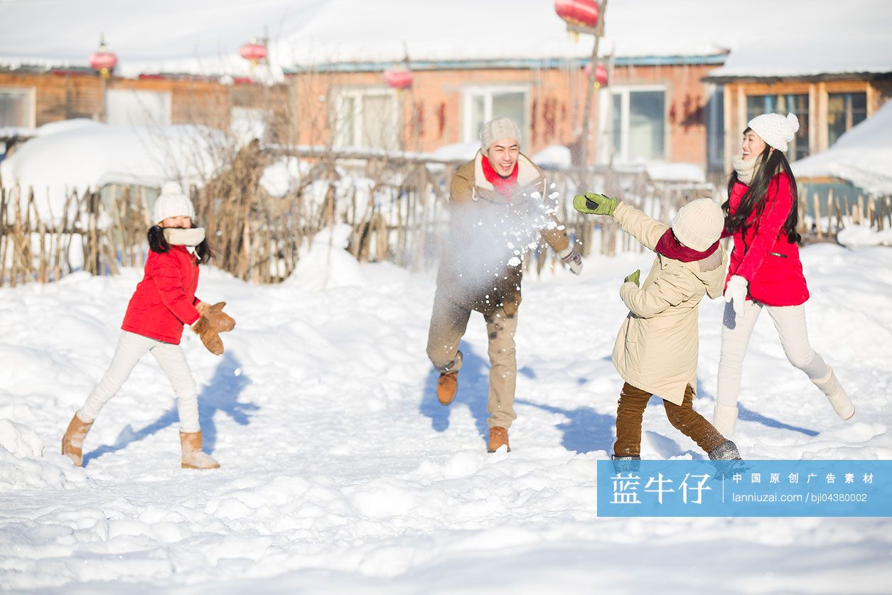 年轻的家庭在雪地上打雪仗