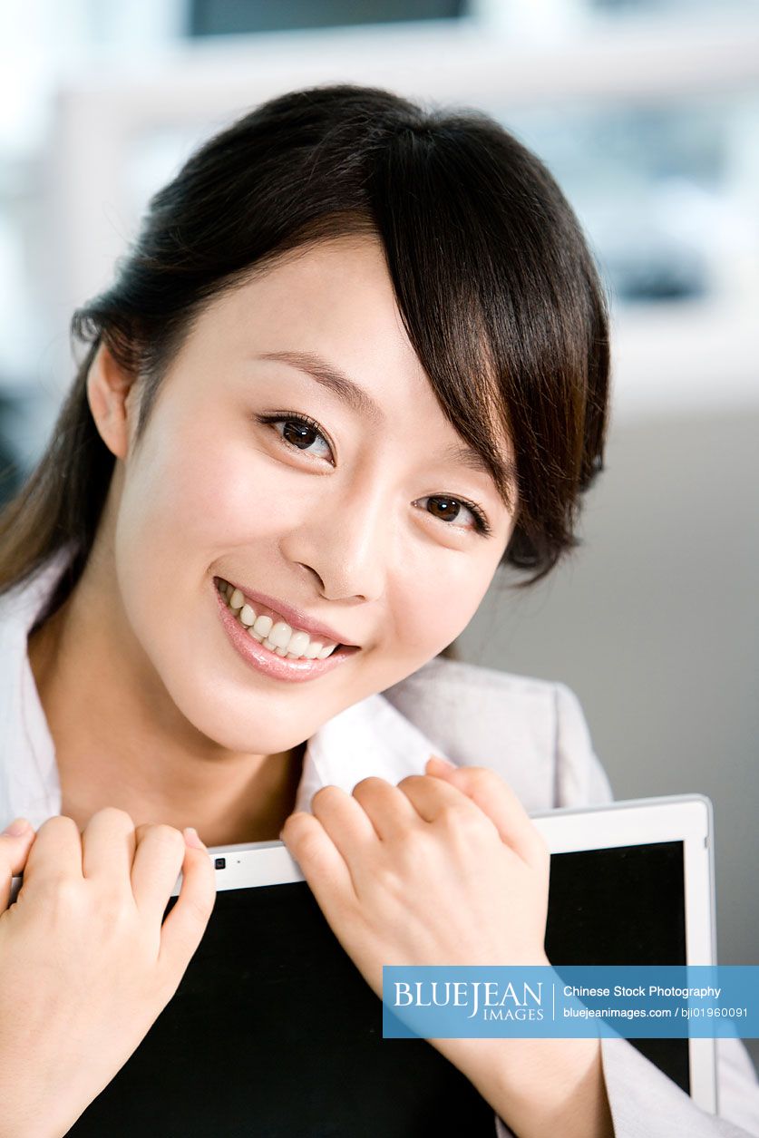 Chinese office worker hugging her computer