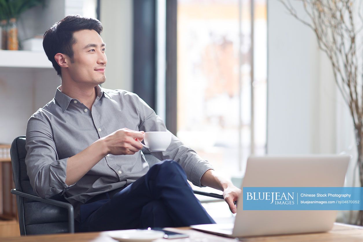 Young Chinese man drinking coffee in office