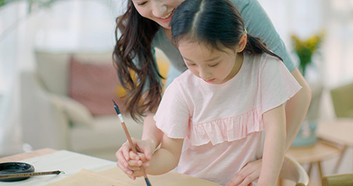 Happy Chinese mother and daughter writing calligraphy at home,4K