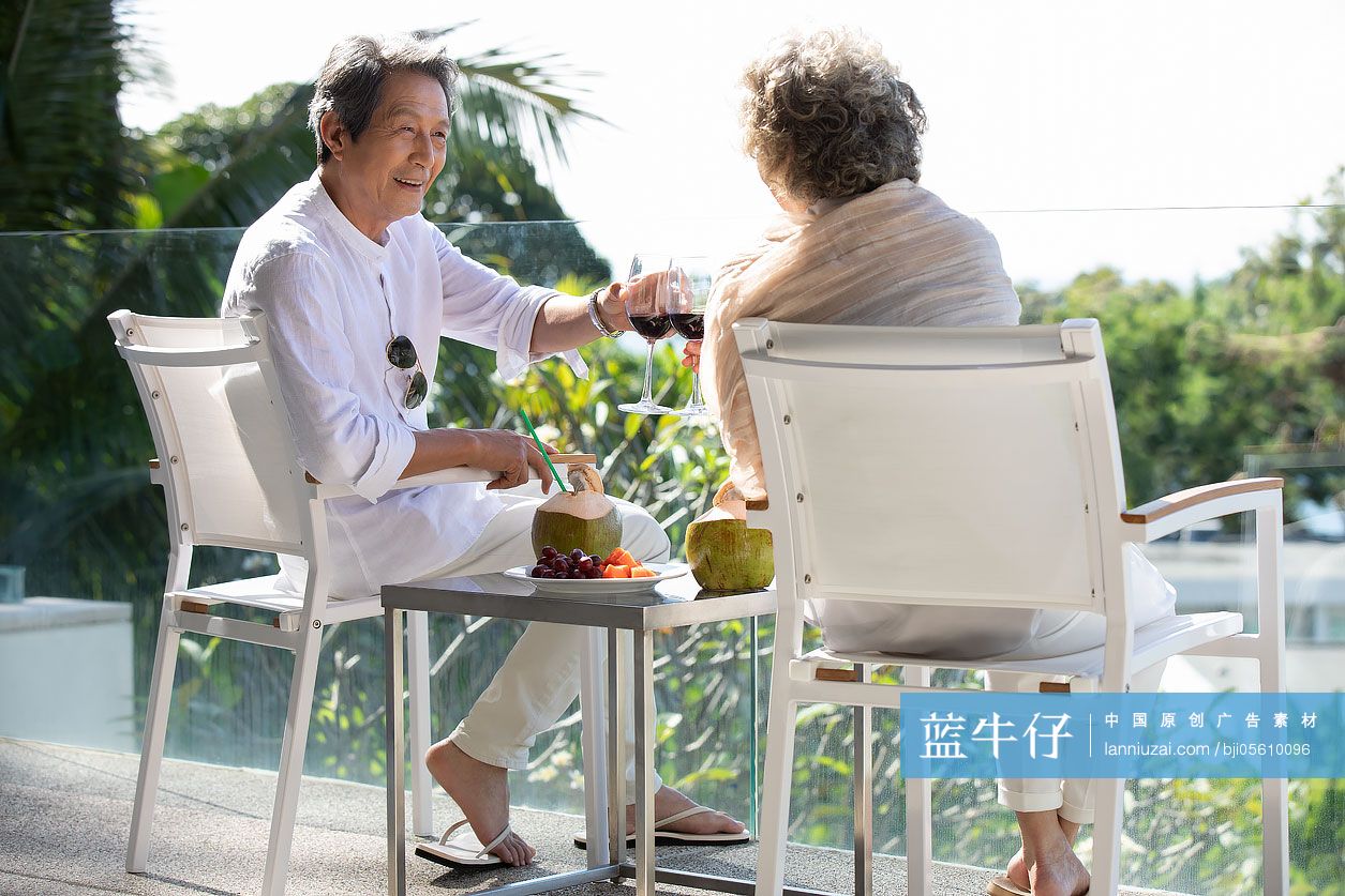 快乐的老年夫妇在阳台喝红酒