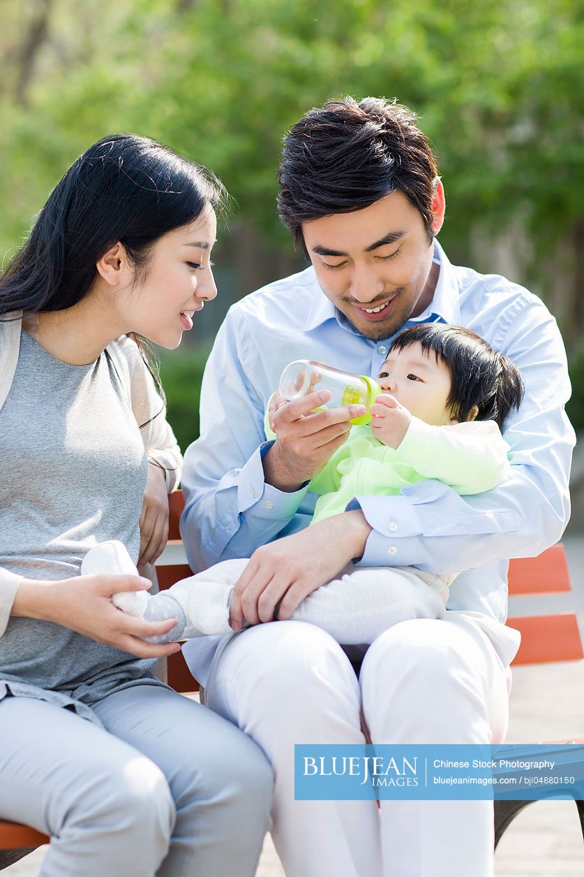 Young Chinese parents feeding their baby