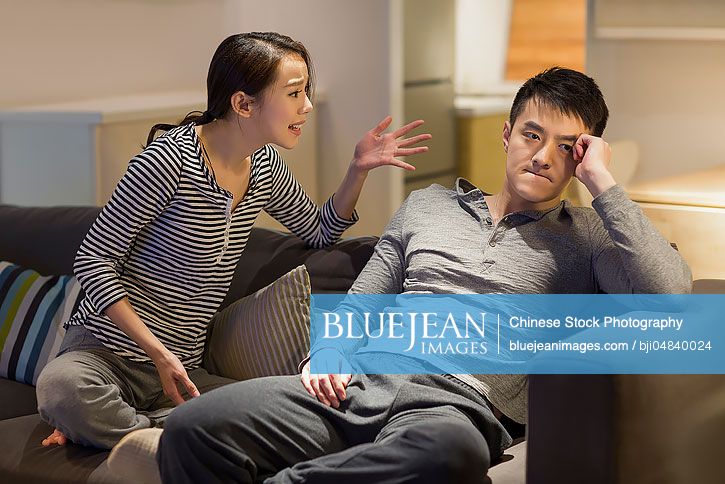 Young Chinese couple arguing on living room sofa