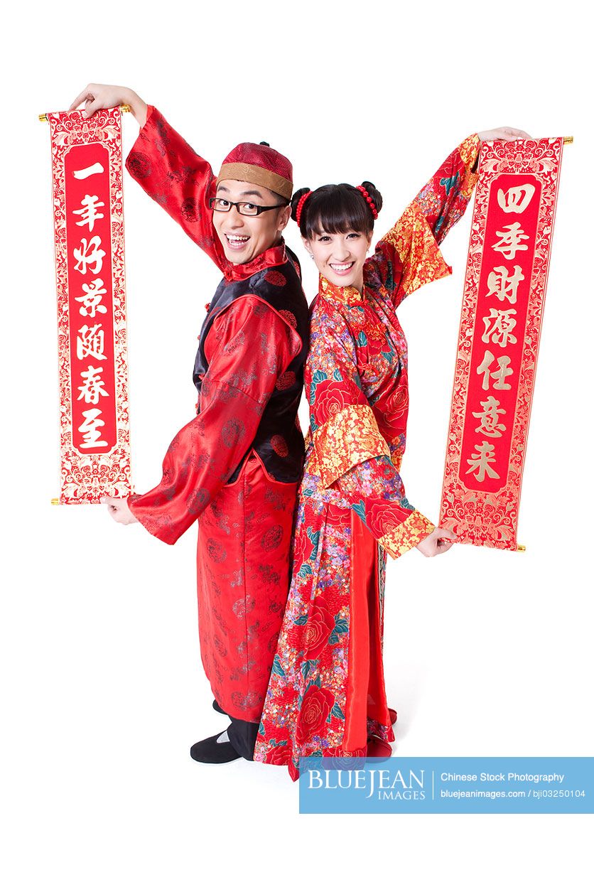 Cheerful Chinese couple in traditional clothing showing Chinese couplets