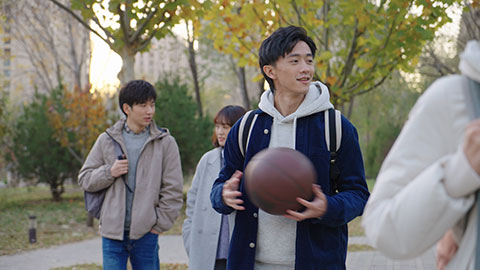 Happy Chinese college boy holding basketball