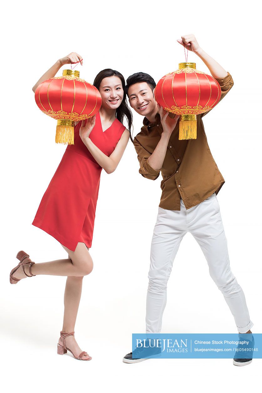 Cheerful young couple celebrating Chinese new year with traditional lanterns