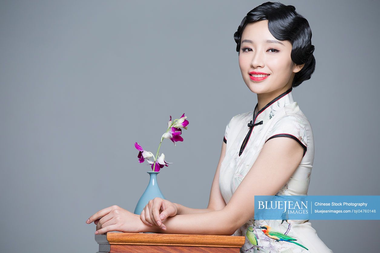 Young beautiful Chinese woman in traditional cheongsam with orchid