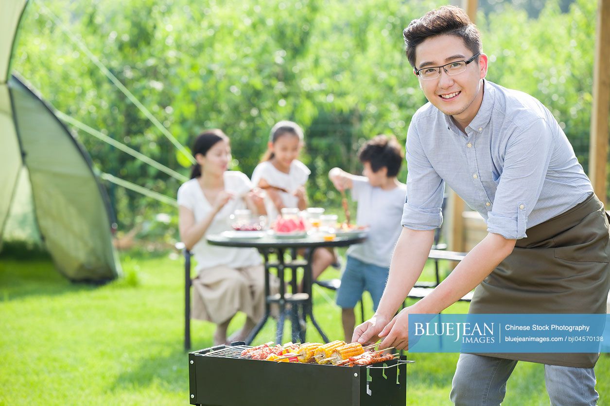 Young Chinese family barbecuing outdoors
