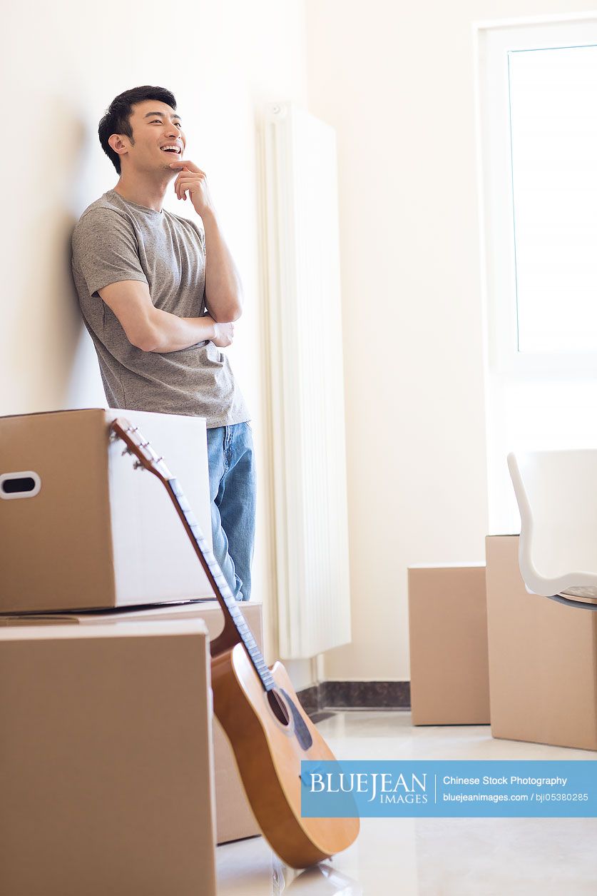 Happy young Chinese man moving to a new house