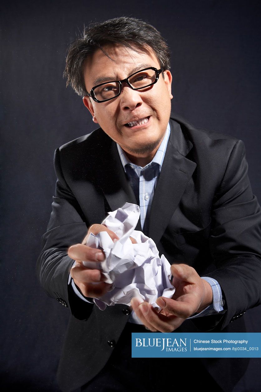 Chinese businessman crushing paper, looking angry