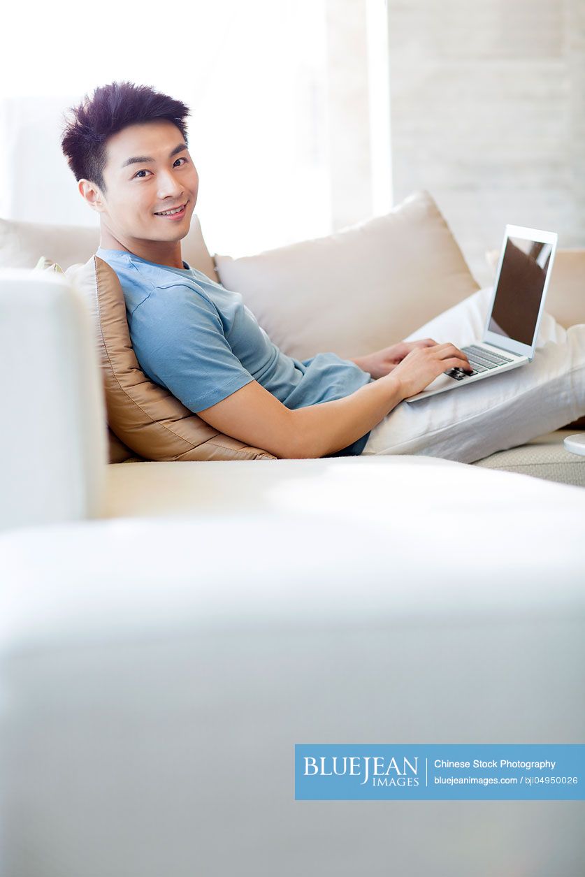 Young Chinese man using laptop on the sofa