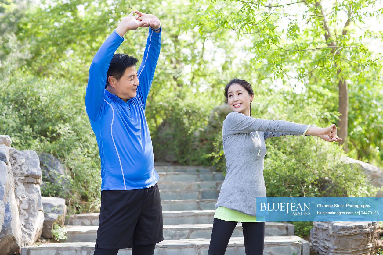 Happy mature Chinese couple exercising in park