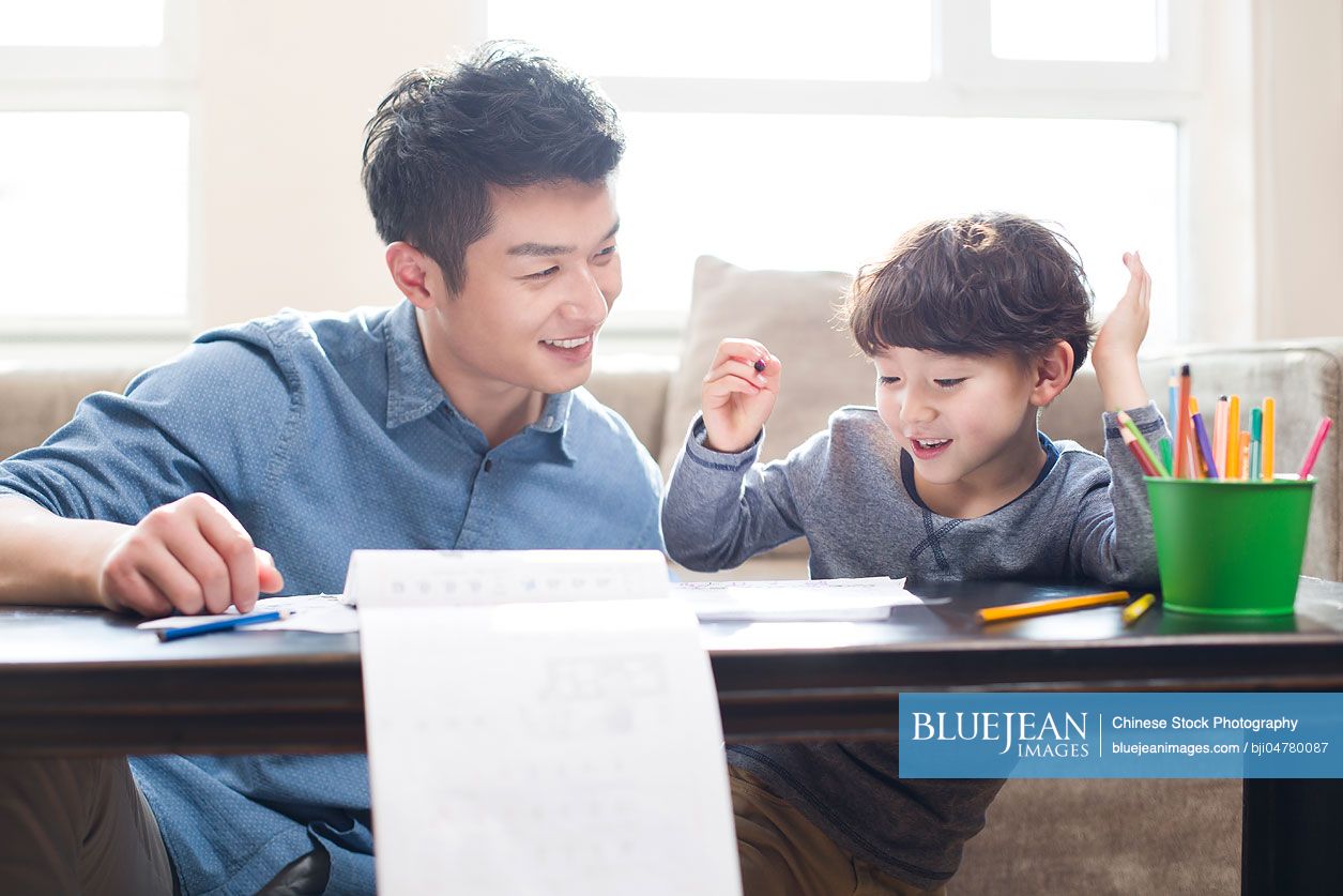 Young Chinese father helping son with homework