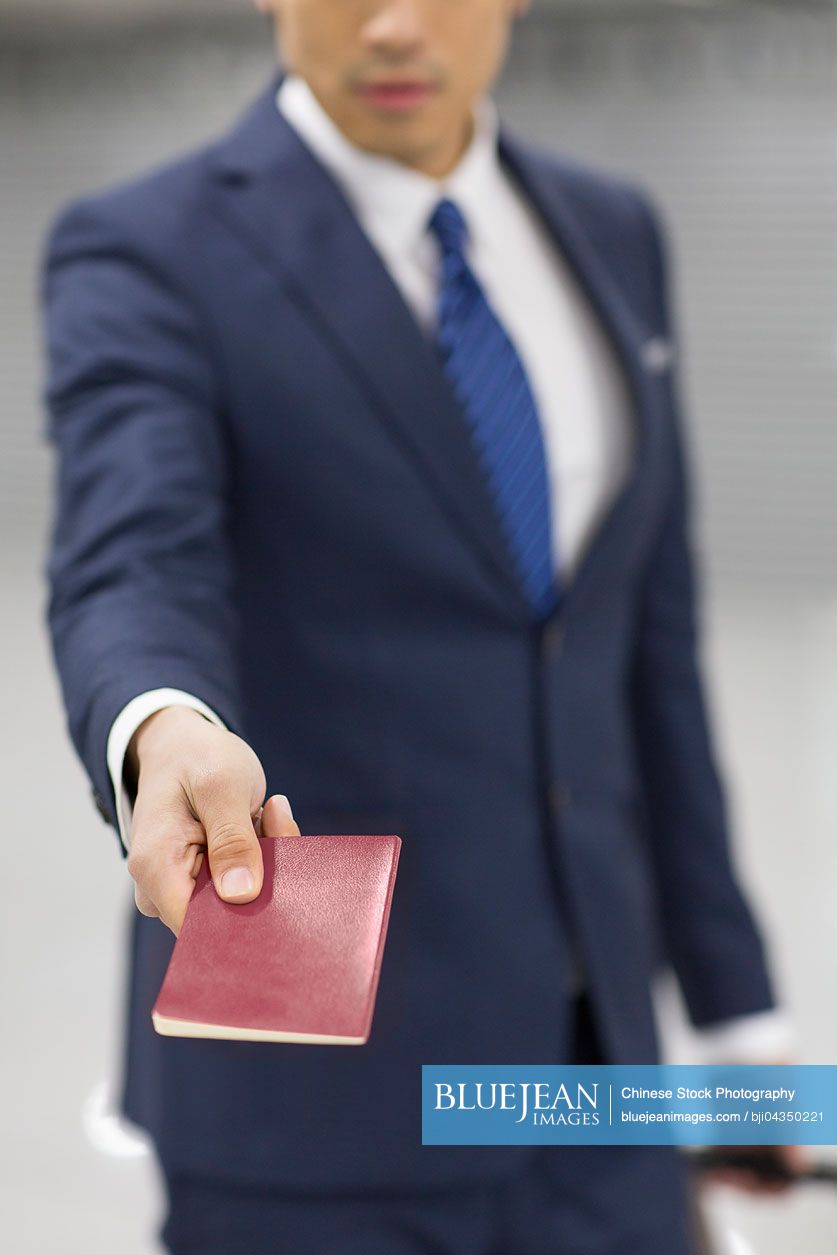 Young Chinese businessman showing his passport in airport