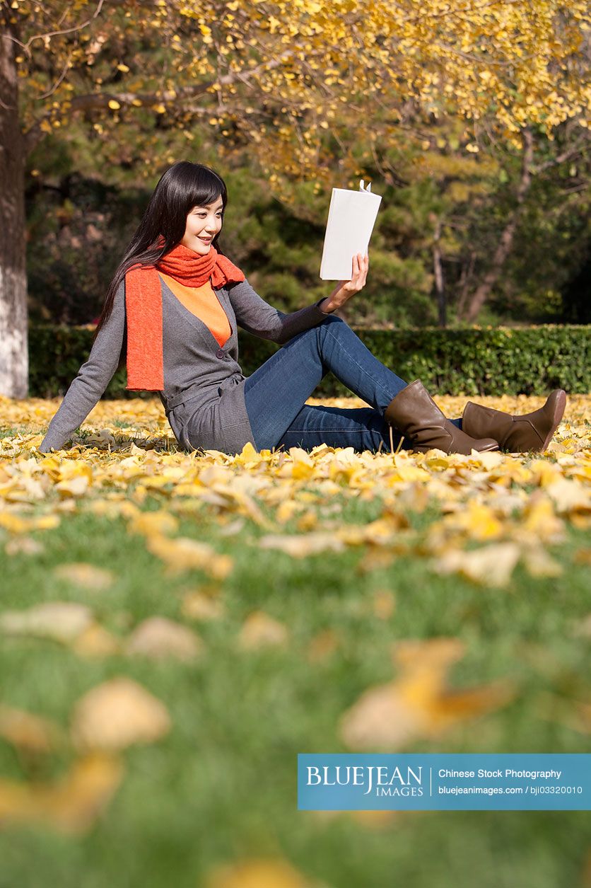 Young Chinese woman reading books in beautiful autumn day