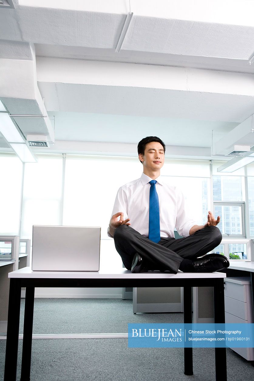Chinese office worker meditating in the office