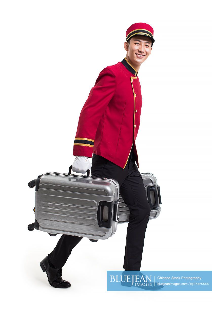 Young Chinese bellboy carrying suitcases