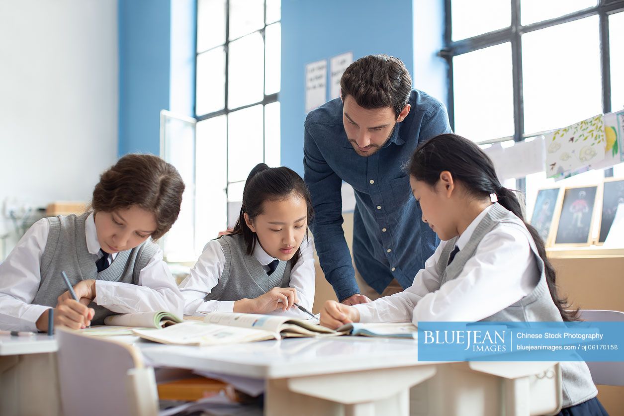 Young teacher helping students in classroom