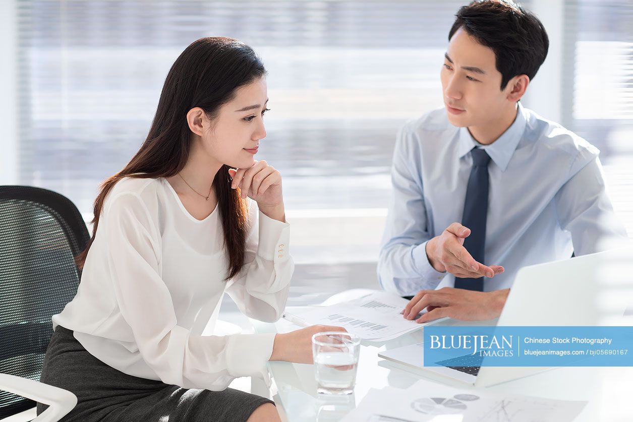 Young Chinese business people using laptop in office