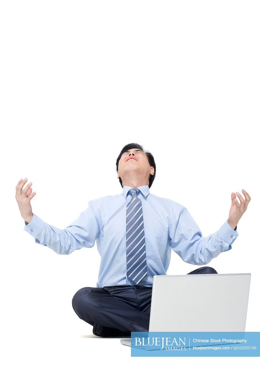 A frustrated Chinese businessman sitting on the floor with his laptop