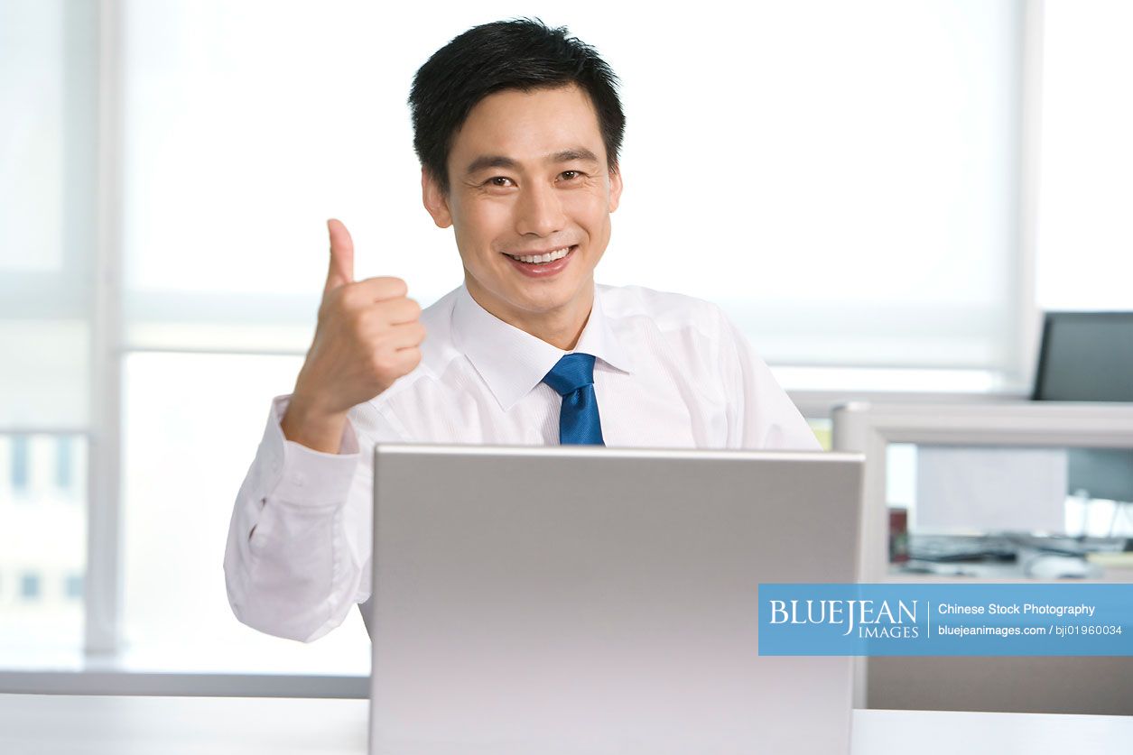 Happy Chinese office worker at his desk