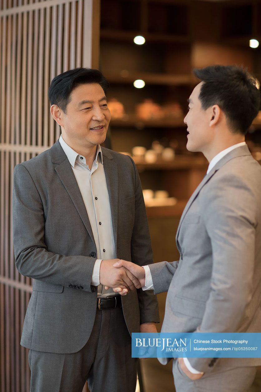 Cheerful Chinese businessmen shaking hands