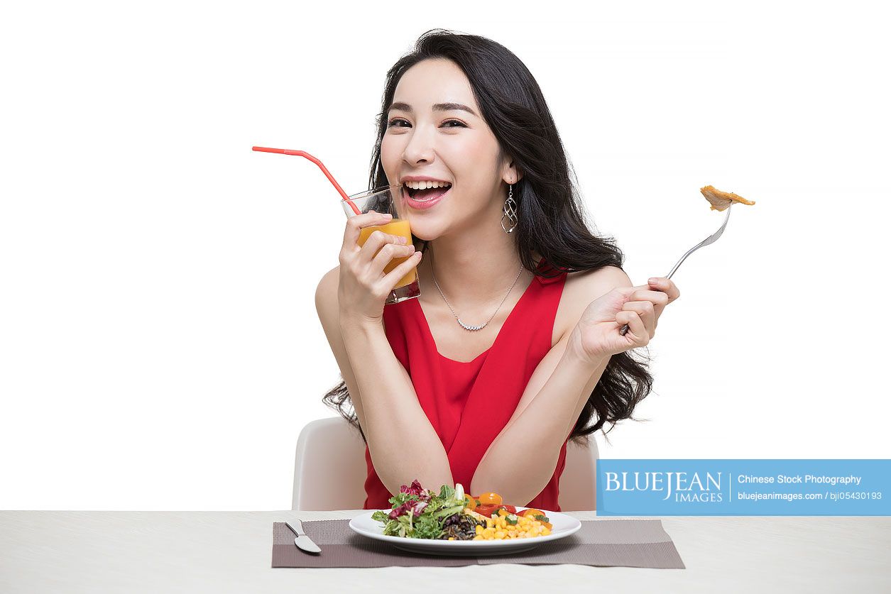 Fashionable young Chinese woman eating vegetable salad