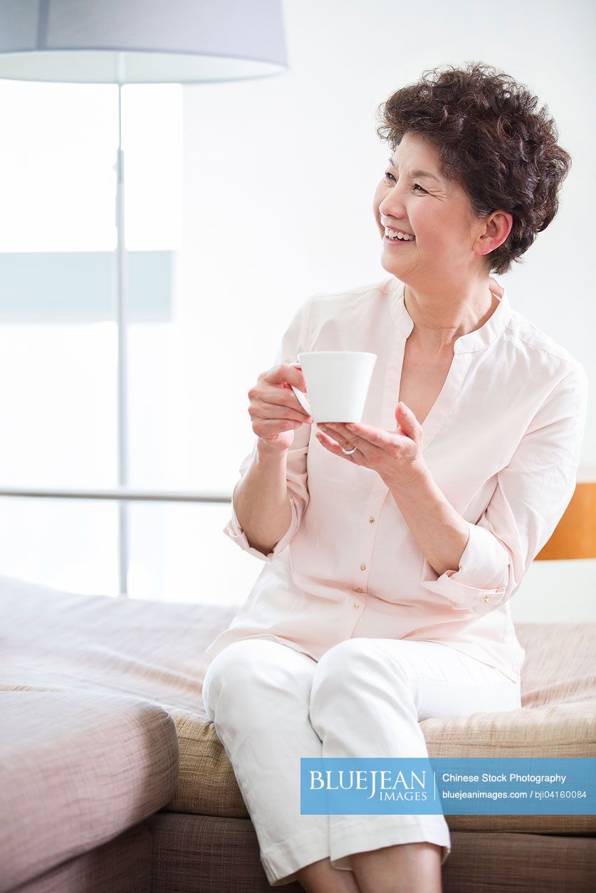Happy senior Chinese woman drinking coffee