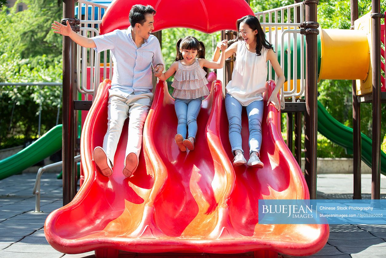 Happy young Chinese family playing in amusement park