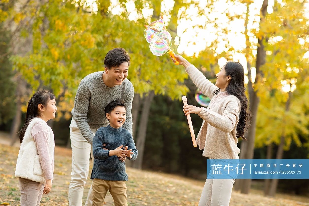 快乐的年轻家庭在树林里吹泡泡