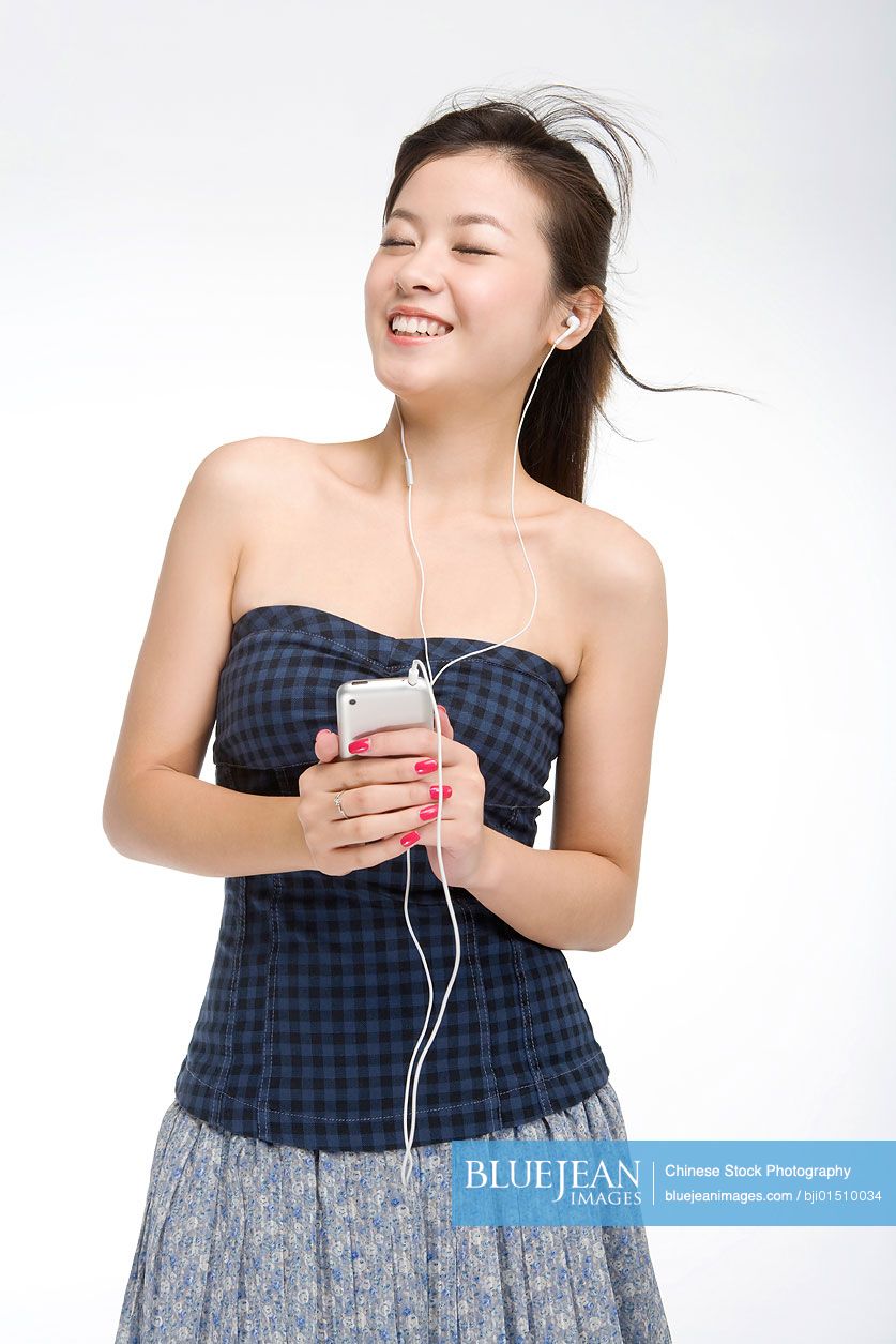 Young Chinese woman listening to music on cell phone