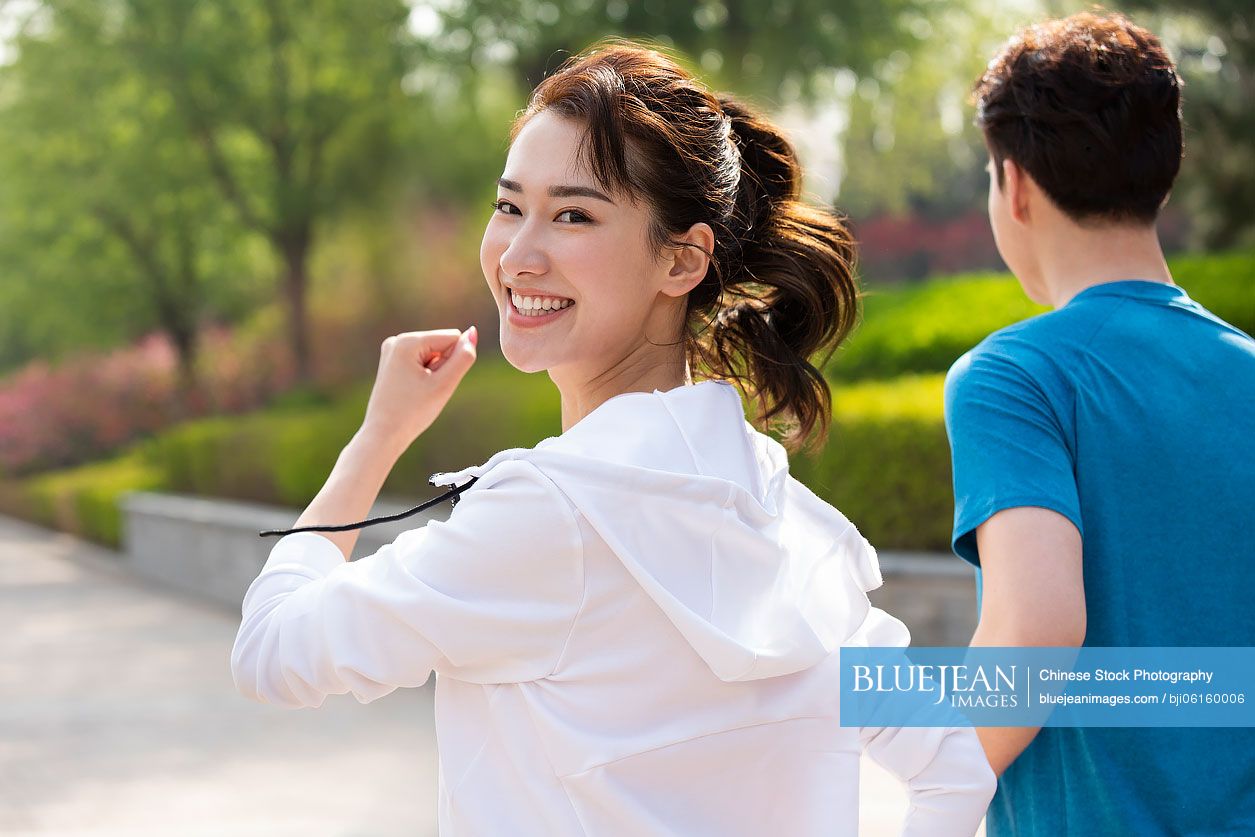 Happy young Chinese couple running in park