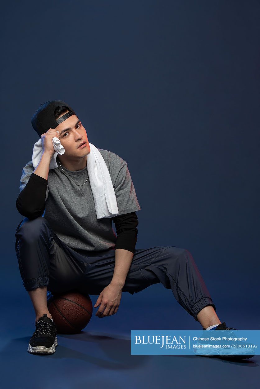 Studio shot of fashionable young Chinese man with basketball