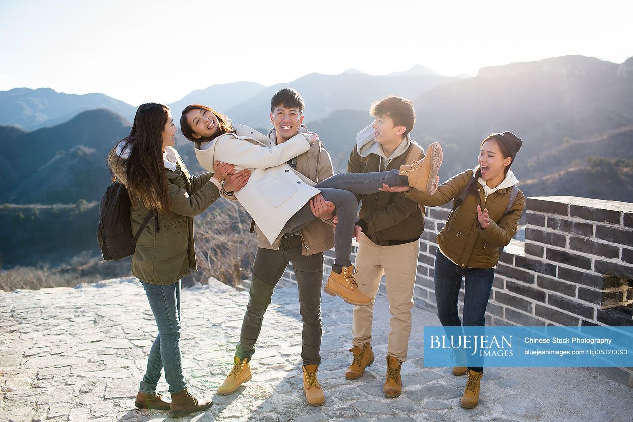 Happy young Chinese friends enjoying winter outing on the Great Wall