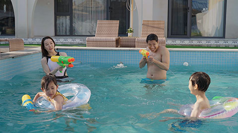 Happy family swimming and playing in the sparkling pool