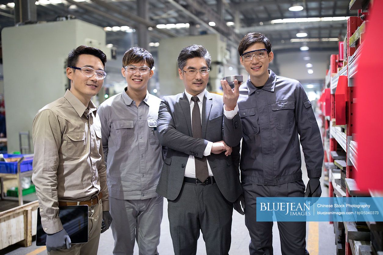 Chinese businessman and engineers checking machine parts in the factory